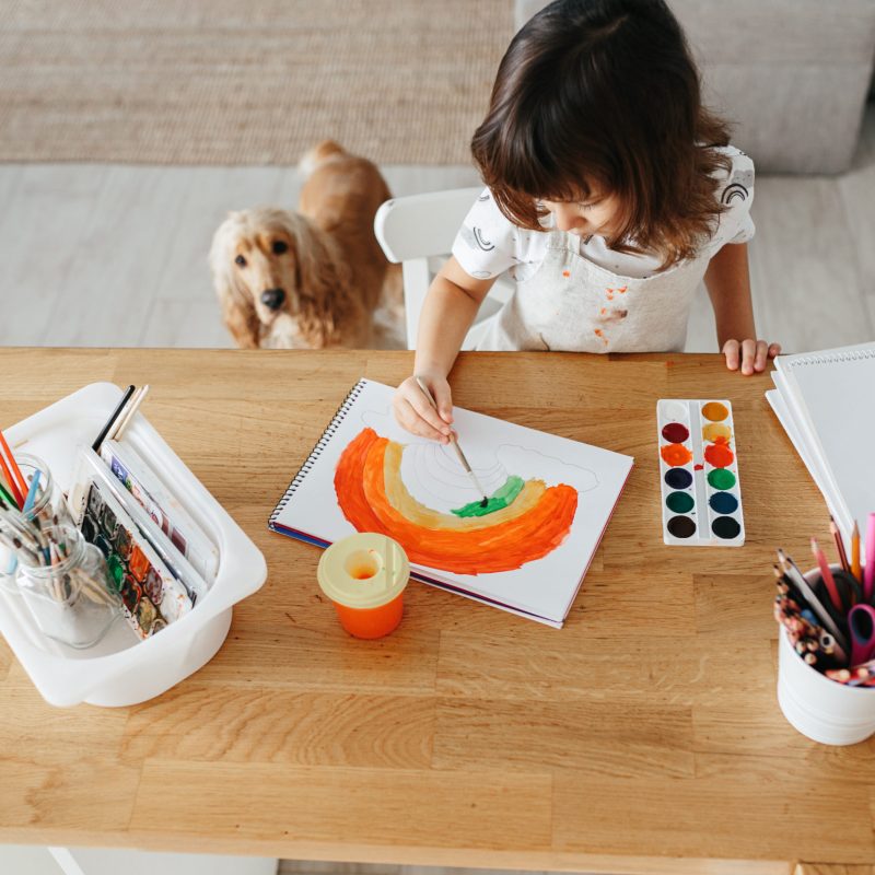 Kids painting watercolor rainbows at table at home. Arts and crafts